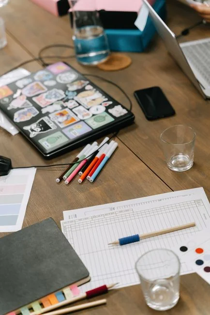 Un bureau lumineux mis en scène avec un livre de design, un ordinateur portable et des outils créatifs, parfait pour stimuler l’inspiration.